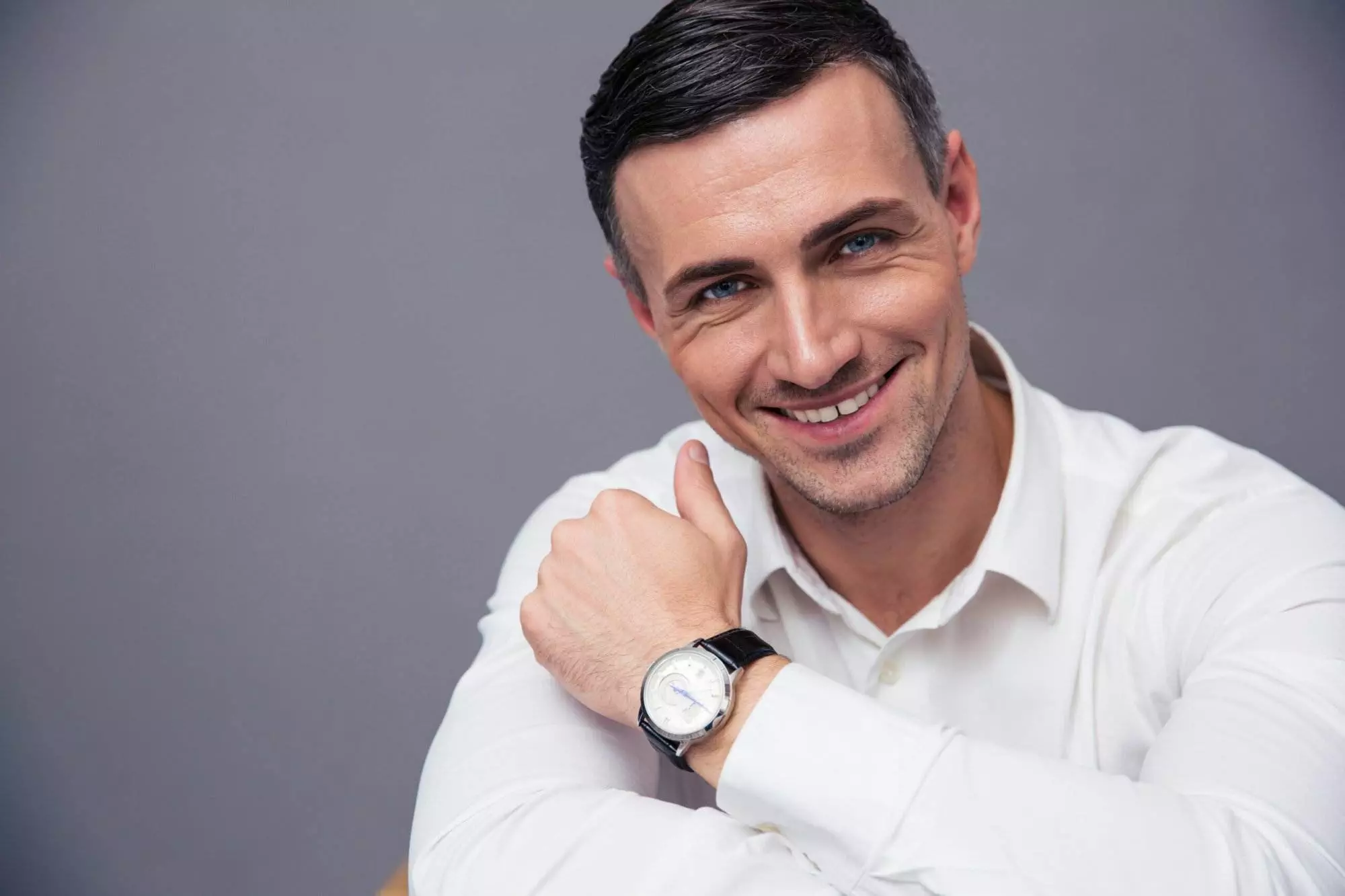 Smiling man in white shirt wearing wristwatch.