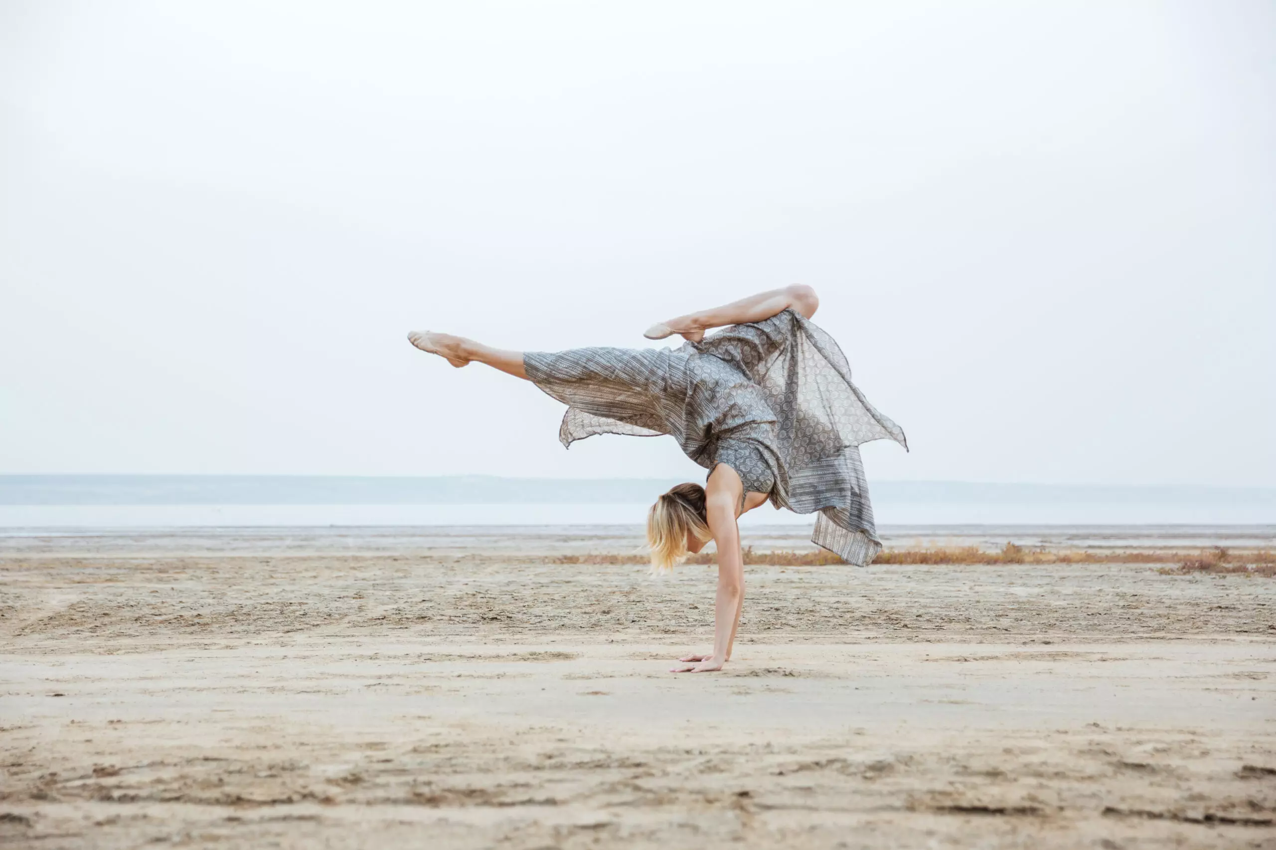 Woman performing handstand on sandy beach