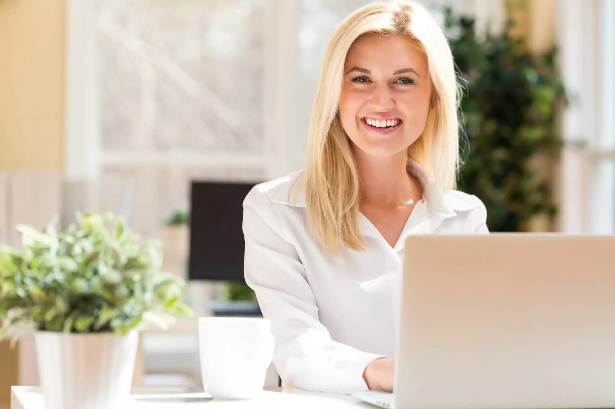 Smiling woman working on laptop indoors.