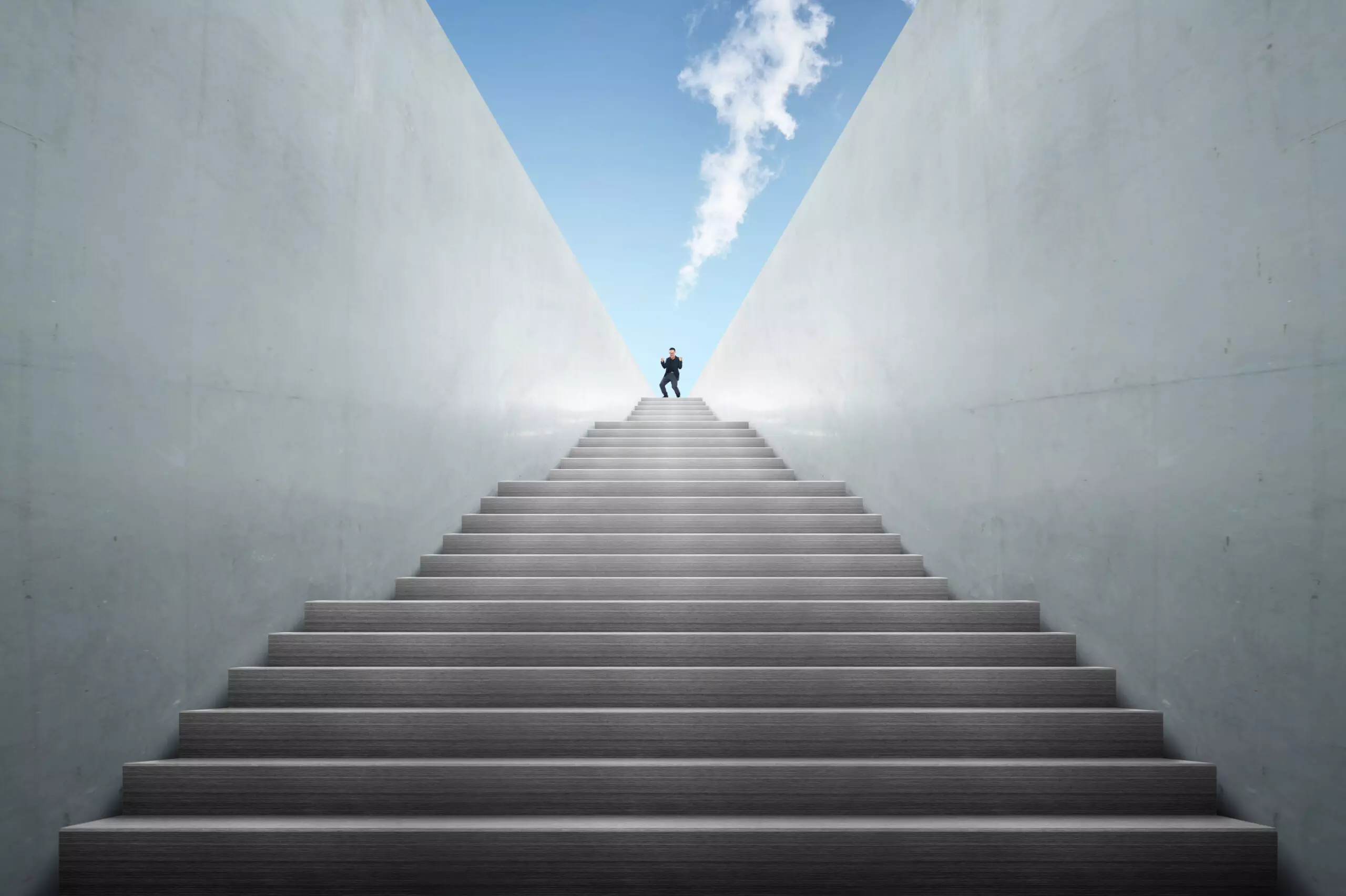 Person ascending modern concrete staircase against sky.
