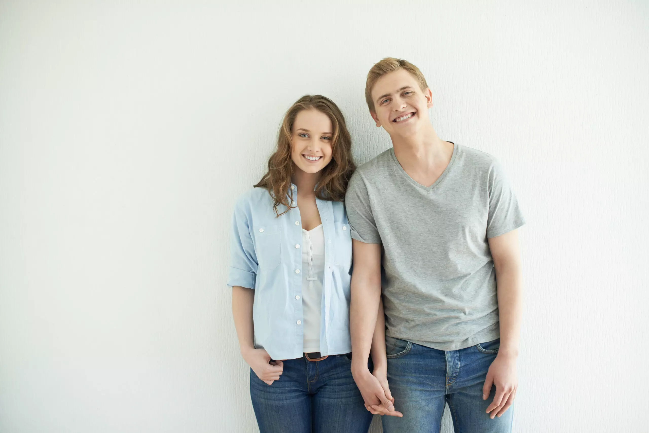Young couple smiling against white background.