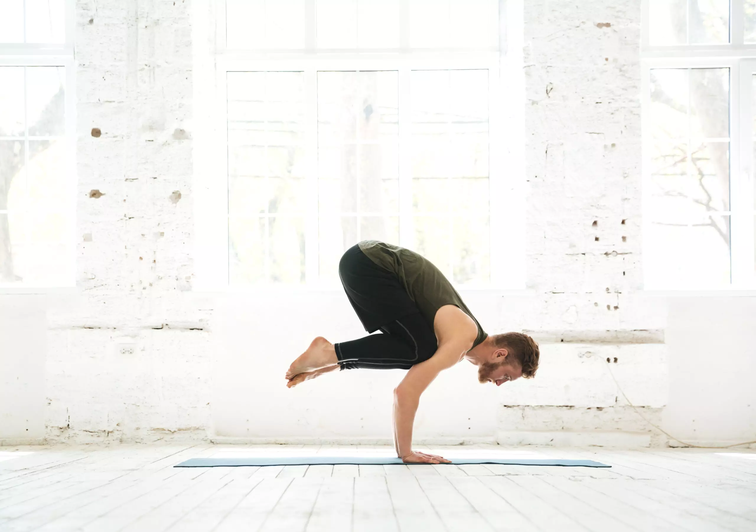 Man practicing advanced yoga pose indoors