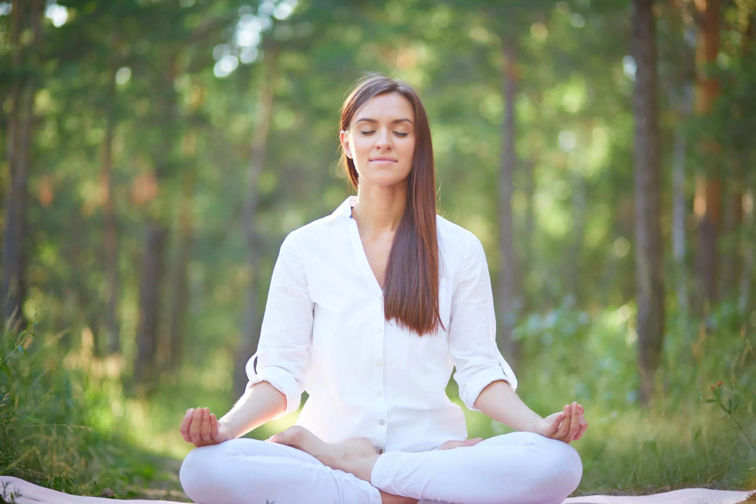 Woman meditating peacefully in forest setting.