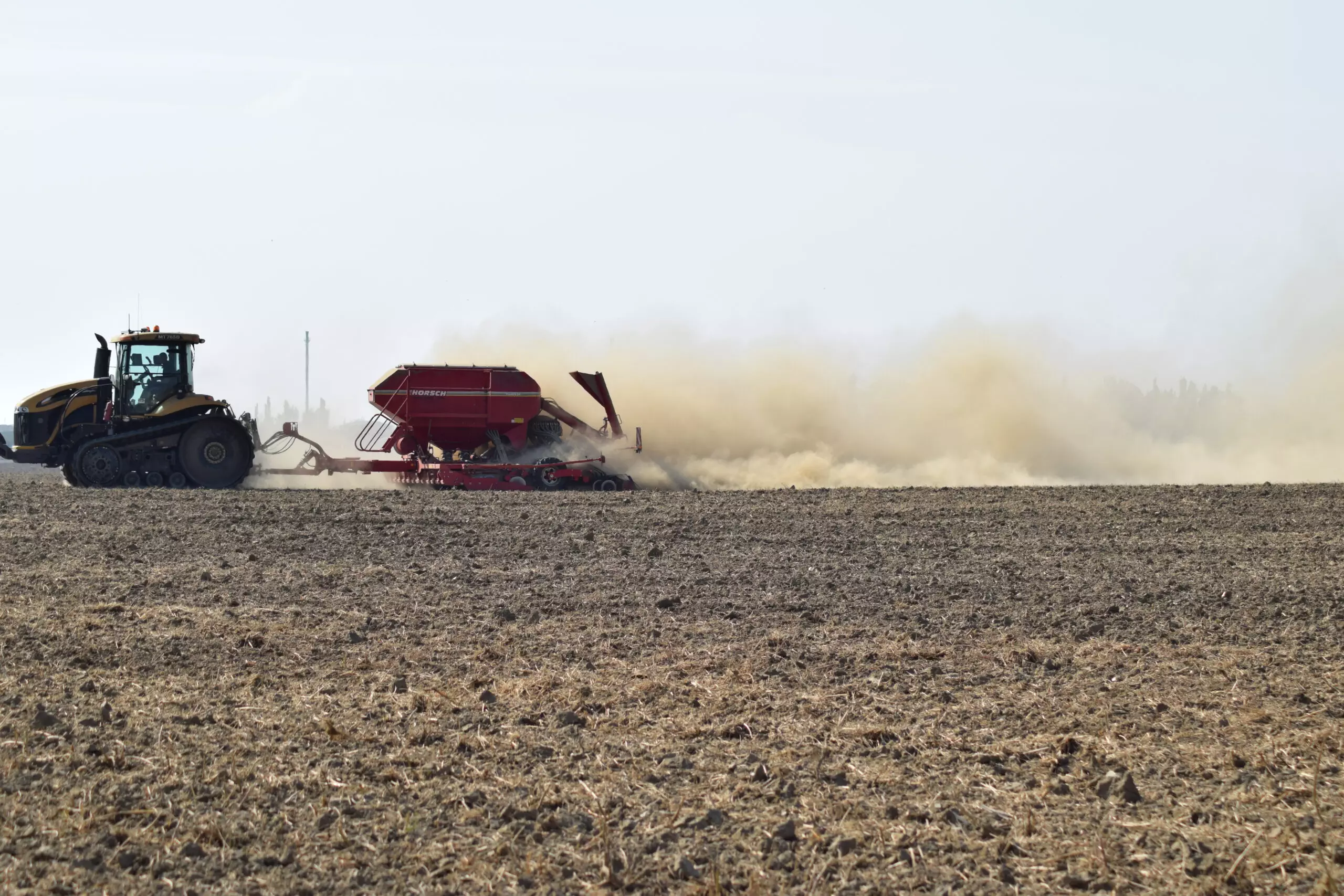 Tractor plowing field with dust cloud.